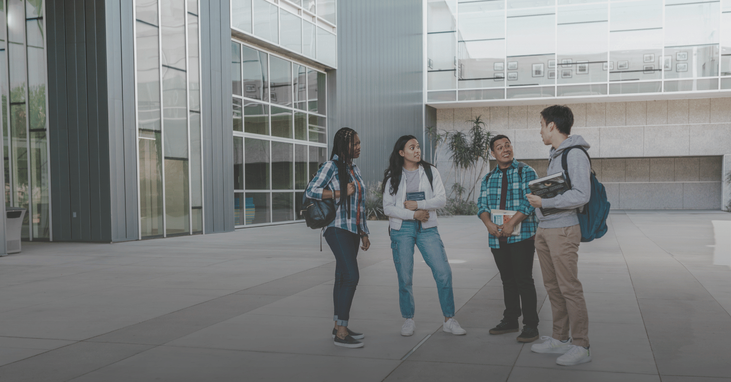 Four students talking outside campus building