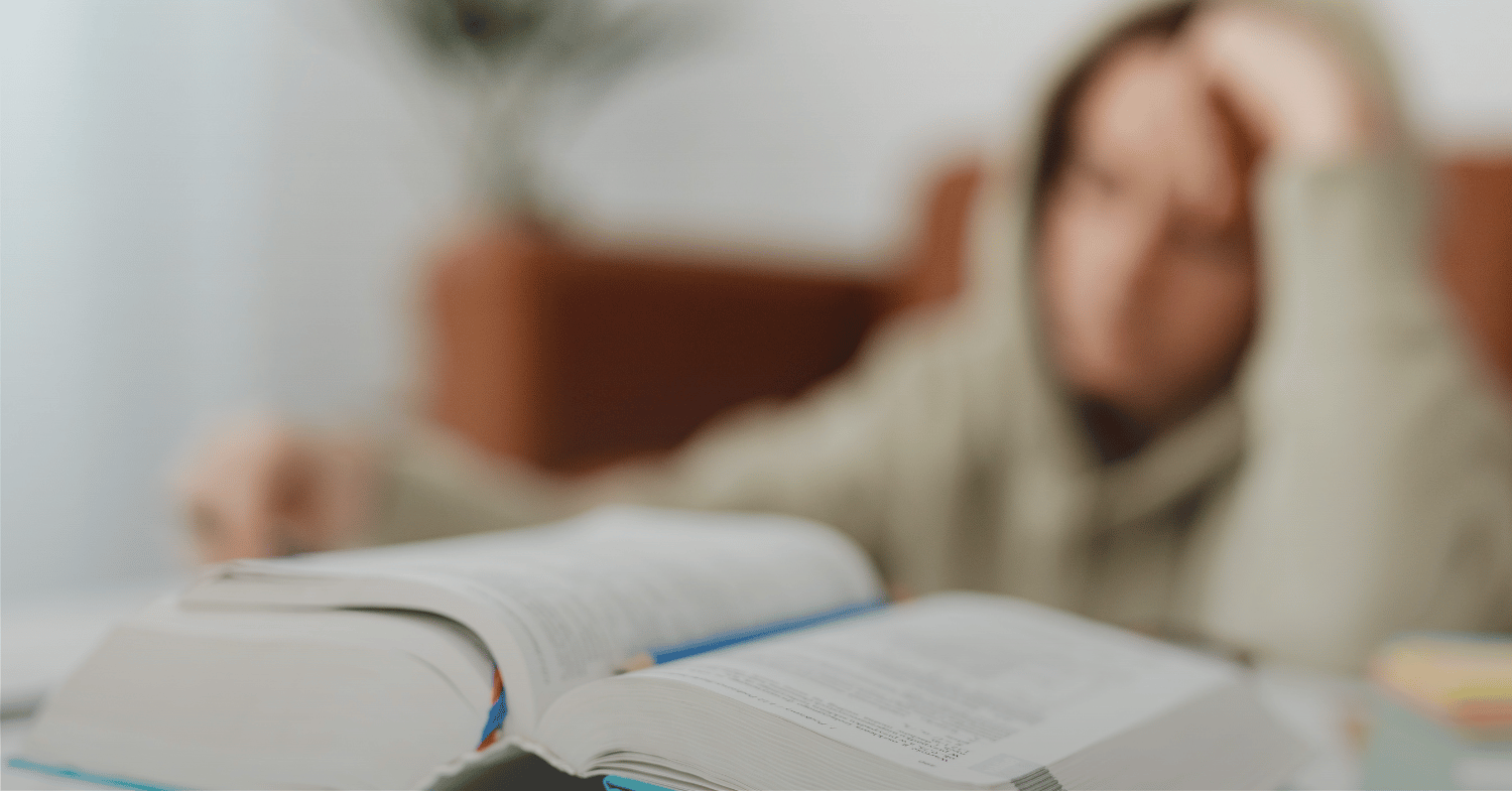 A thick book with a student in the background stressing