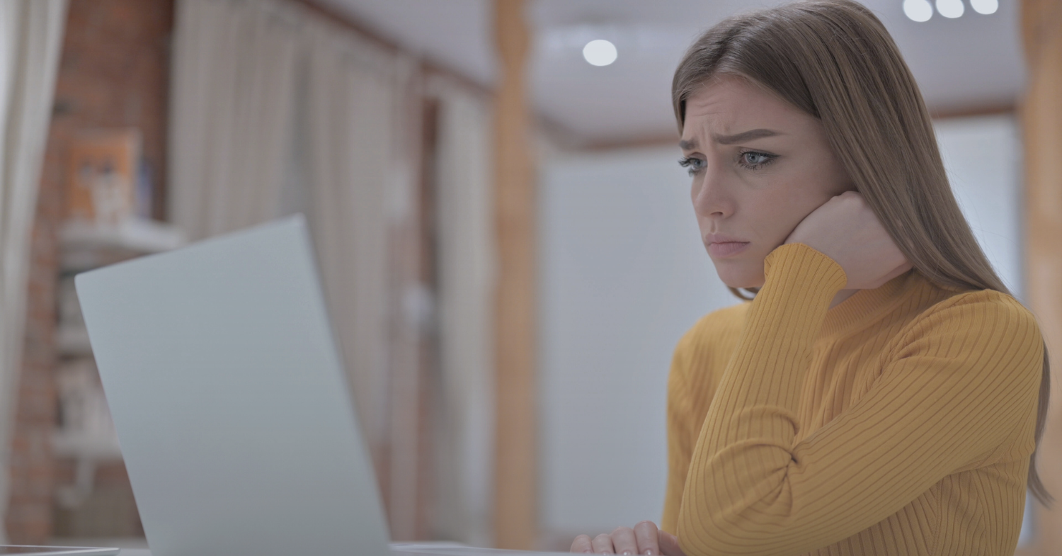 Female student looking disappointed in front of computer screen