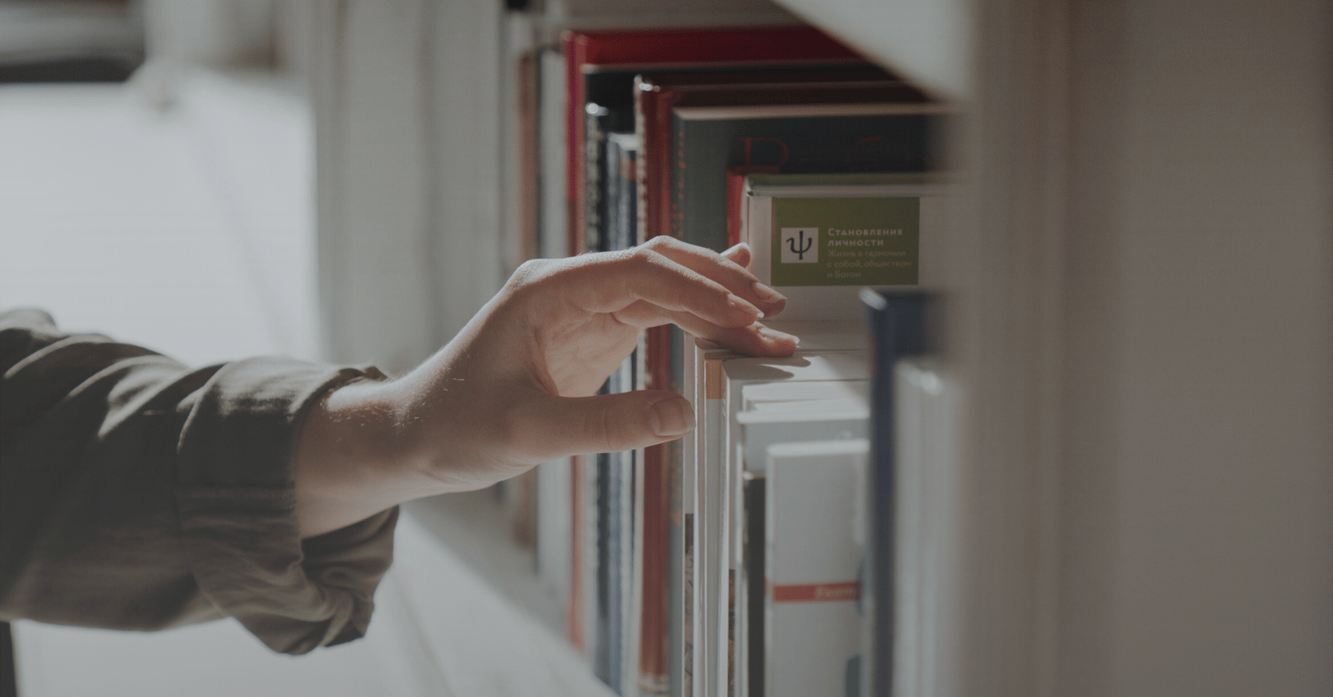 Hand reaching for a book on a bookshelf