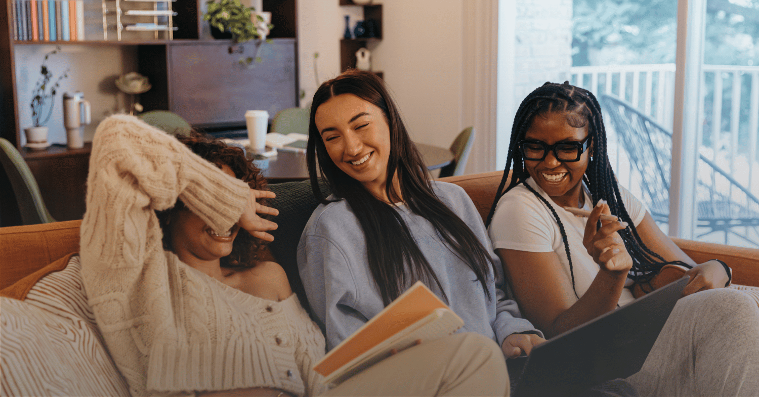 Three female students sitting on a couch, joyfully chatting