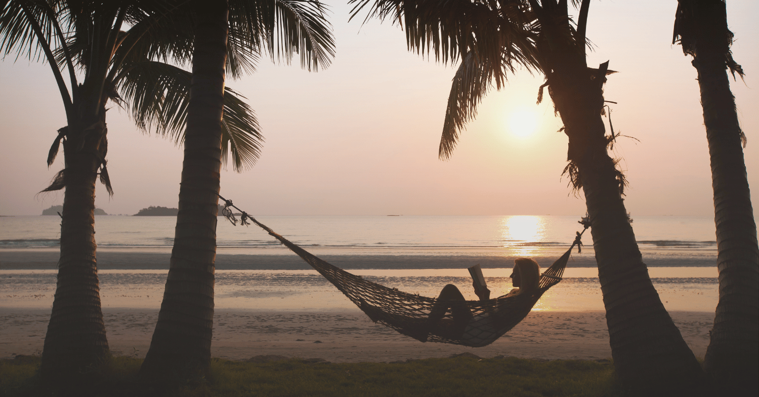 girl reading book on a hammock at the beach