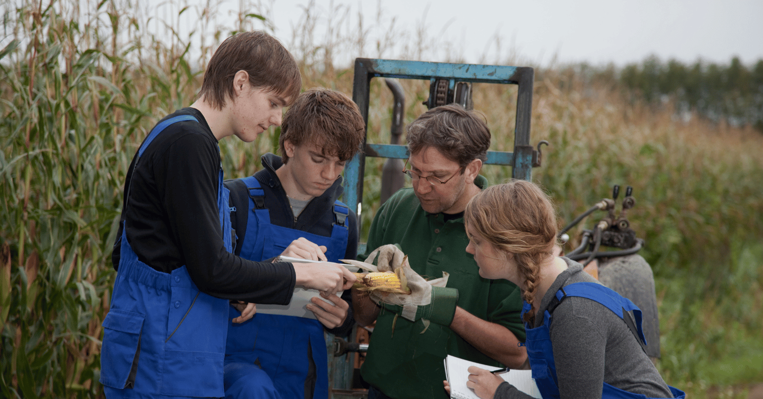 3 students on a field trip to a farm with a farmer